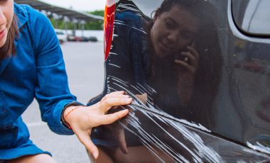 woman stand near scratched car looking for cheap car insurance for young drivers