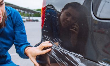 Girl looking at her car and inquiring on call about car insurance cover scratches and dents