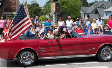 Red Ford Mustang with military Veterans during memorial day parade