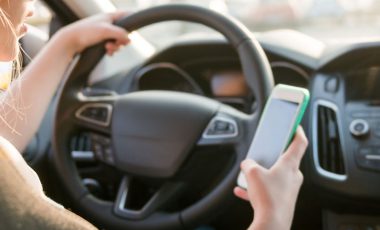 A girl is driving a car while using her phone on the roads of tennessee.